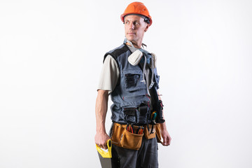 Fototapeta premium The builder in a helmet, and unloading, holds a hacksaw in his hands on a tree. On a light background.