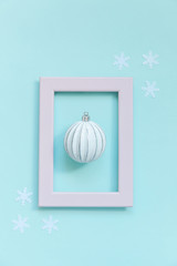 Simply minimal composition winter objects ornament ball in pink frame isolated on blue pastel trendy background. Christmas New Year december time for celebration concept. Flat lay top view
