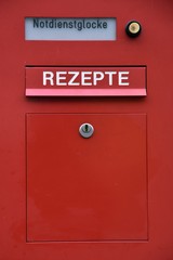 Roter Briefkasten einer Apotheke für Rezepte mit Notdienstglocke