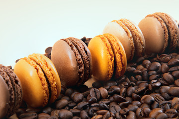 Various colorful macaroons in a row and coffee beans