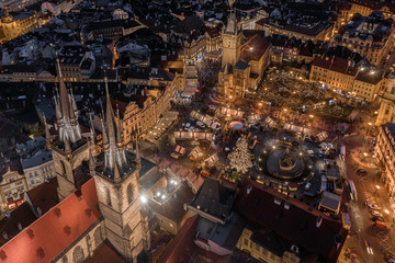 Prague, Czech Republic - Aerial drone view of the famous illuminated Church of our Lady Before Tyn towers at blue hour with traditional Christmas market, Old Town Square & Old Town Hall at background