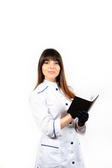 Beautiful smiling young female doctor in white medical jacket isolated on white background. Brunette woman cosmetologist holding books, notebook, folder. Space for text.