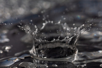 Water drops hitting against a black surface.