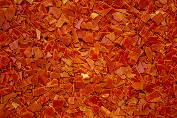 Shards of red flat plastic lying in bulk on the surface.