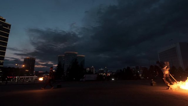 Fire show performers makes a lot of flame with flamethrower. Artists light up flaming sparkls. Fire stream up. Rushing fire jet in sky. Hot dangerous show. Cityscape. Slow motion footage.