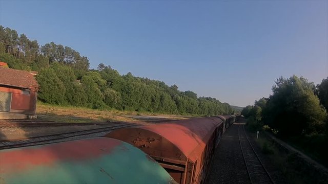 FPV drone shot flying over a rusty old train on an empty station