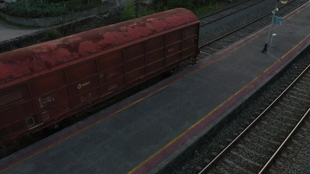 Aerial shot of a rusty old train wagon revealing train tracks. RISING TILT DOWN