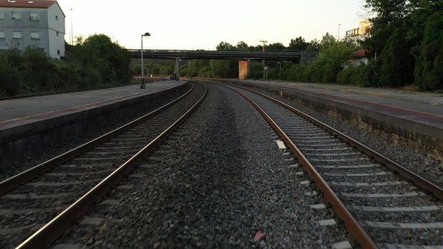 Aerial rising over railways of an empty station at sunset
