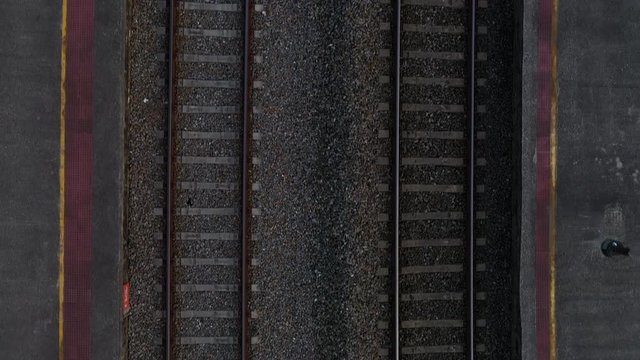 Aerial tilt reveal of train tracks and an old train in the middle of the mountains