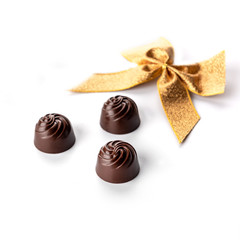Chocolate pralines o white background with golden ribbon