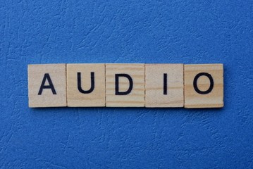 word audio made from gray wooden letters lies on a blue background