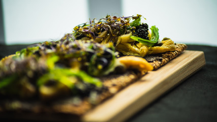 Tostada de tortilla con olivada y algas sobre tabla de madera