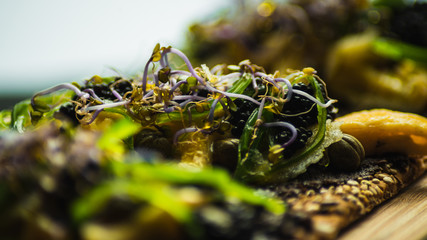 Tostada de tortilla con olivada y algas sobre tabla de madera