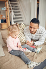 High angle portrait of cute little girl showing I love you card to dad while enjoying time together in home interior