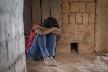 Unhappy depressed teenager with face in hands sitting lean against the wall