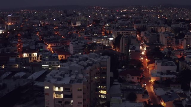Flight on drone above Limassol buildings at night. Evening cityscape of mediterranean resort of Cyprus, aerial footage