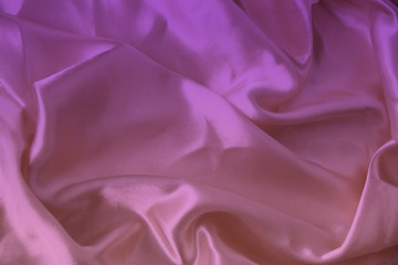 beautiful luxury texture of silk draped fabric with tints of pink, purple, top view, close-up, copy space