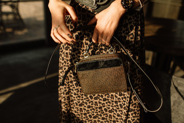 Close up fashion details, young business woman holding bag, warm colors. leopard skirt, brown color