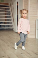 Full length portrait of cute little girl wearing pink shirt posing in cozy home interior, copy space