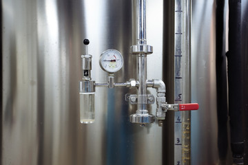 Pressure gauge and valve connected with steel tank in craft brewery
