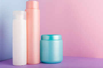 Set of cosmetic products on pink background. Cosmetic package collection for shampoo, mask, conditioner, shower gel. Pink, white, blue plastic bottles, jar for packaging cosmetics Mock up, copy space
