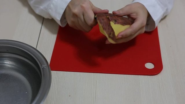 Woman hands peeling of poteto.