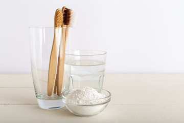 Bamboo toothbrushes, glass of water, dentifrice tooth powder on white background. Biodegradable natural bamboo toothbrush. Eco friendly, Zero waste, Dental care Plastic free concept. Morning routine