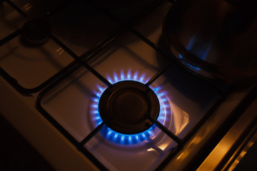 Gas burner on white modern kitchen stove. Kitchen gas cooker with burning fire propane gas.