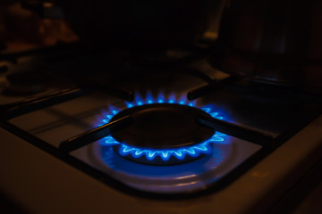 Gas burner on white modern kitchen stove. Kitchen gas cooker with burning fire propane gas.