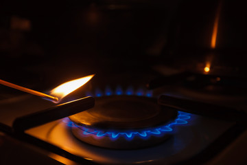 Gas burner on white modern kitchen stove. Kitchen gas cooker with burning fire propane gas. A man lighting the gas-stove with a match.