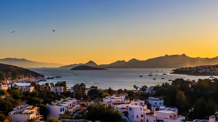 Fototapeta na wymiar Bright colorful sunset in the beautiful bay of the Aegean sea with islands, mountains, boats and birds in the sky . Summer holiday concept and travel background