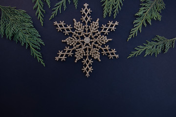 Gold snowflakes with greenery on a dark background
