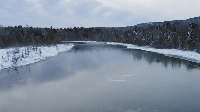 Aerial flight down frozen river Winter wonderland 