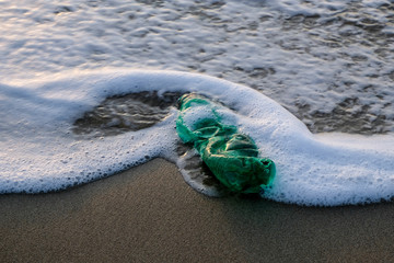 Fototapeta na wymiar Green plastic bottle on ocean sea water foam,ecosystem pollution free concept