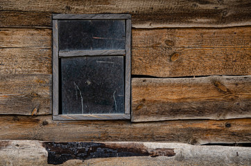 A small window in the wall of an old wooden shed.