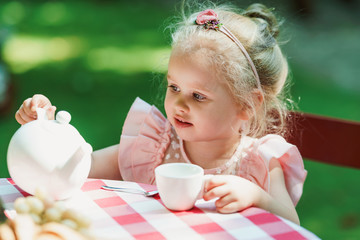 Little girl having a tea party in the backyard