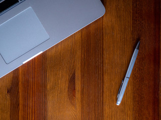 Laptop i długopis na drewnianym stole - obrazy, fototapety, plakaty
