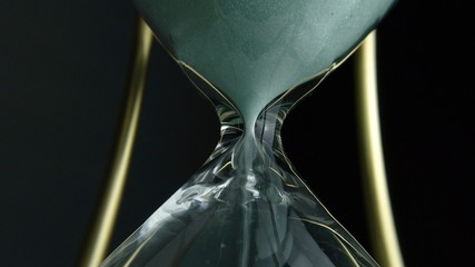 Extreme close up view of sand flowing through an hour glass. Super closeup of hourglass clock...