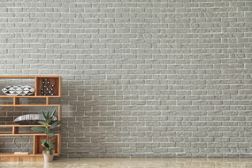 Wooden shelving unit with plant in pot and decor near brick wall
