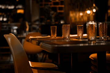 Cozy interior of restaurant or cafe with soft warm light of lamps in evening. Elegantly served...