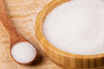 Bowl full of granulated sugar on a wooden background
