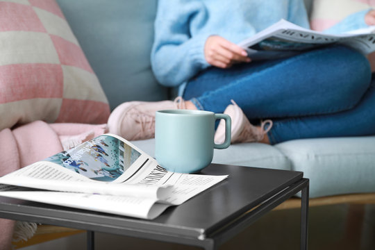 Newspaper and cup of coffee on table in room