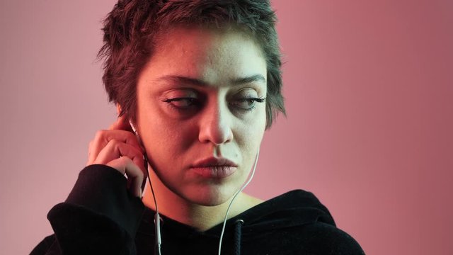 Close-up teenage girl listening to music on headphones in neon rays. 4k