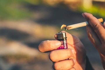 Men hand caught a burning cigarette causing smoke, concept stop smoking.