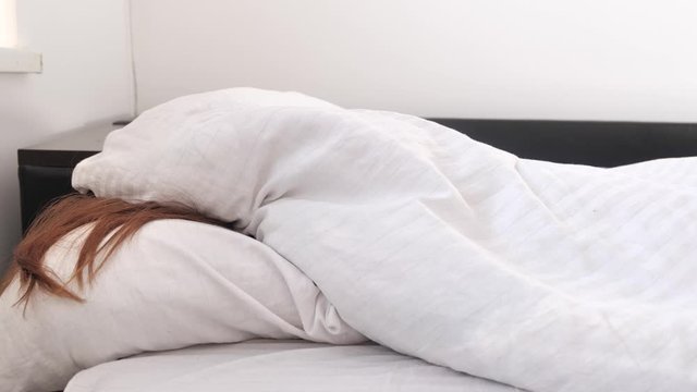 Lazy weekend wakeup, young adult woman does not want to get out of bed , white bedroom lit by morning sun. Girl idly pandiculate and don't want to leave soft place 4k