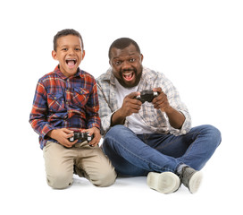 Portrait of African-American man and his little son playing video game on white background