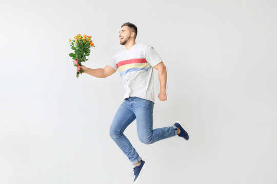 Handsome Jumping Man With Flowers On Light Background. Valentine's Day Celebration