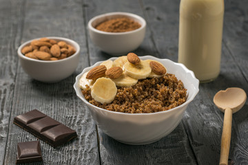 Quinoa and cocoa porridge with almond milk and nuts on a wooden table.