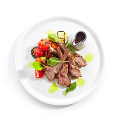 Grilled Lamb Rack with Baked Vegetables on White Restaurant Plate Top View