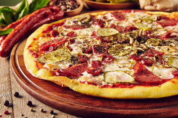 Meat and vegetable pizza on wooden table close up
